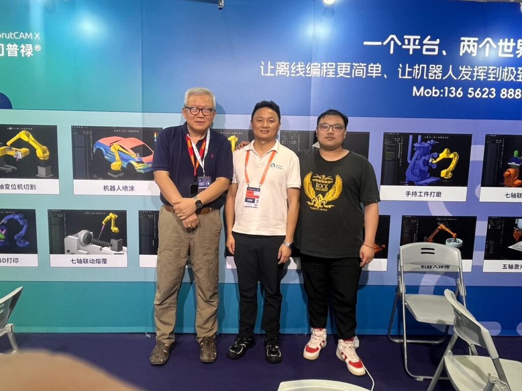 Three men pose together in front of colorful exhibit panels.