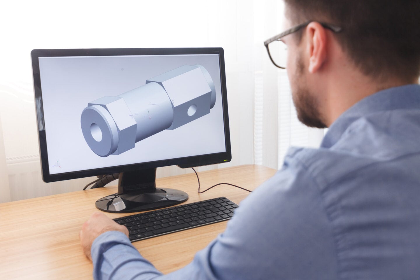 An engineer analyzes a 3D model on a computer screen.