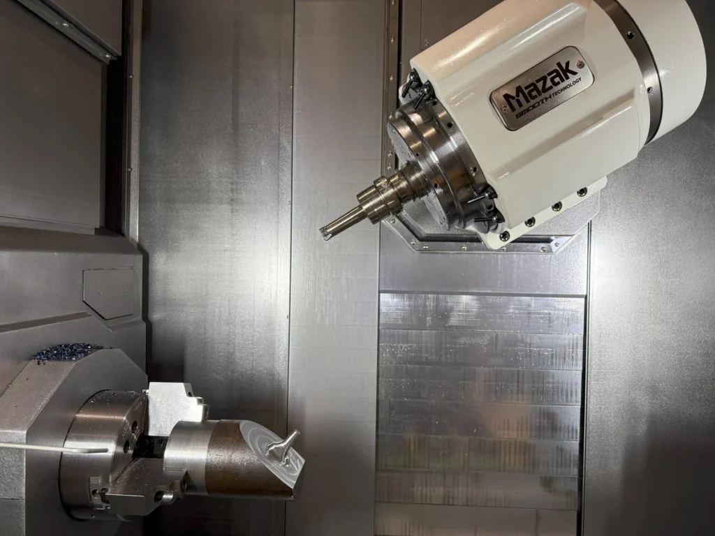 A robotic arm operates a lathe, shaping metal components.