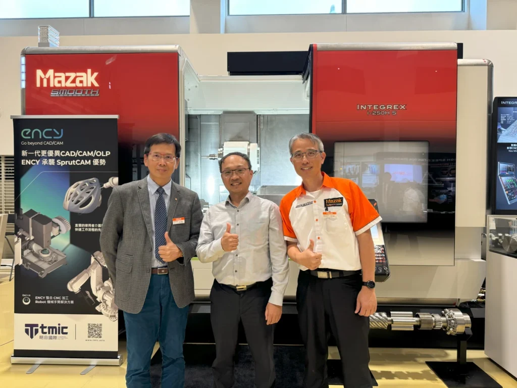 Three men pose with thumbs up in front of a machine at an event.