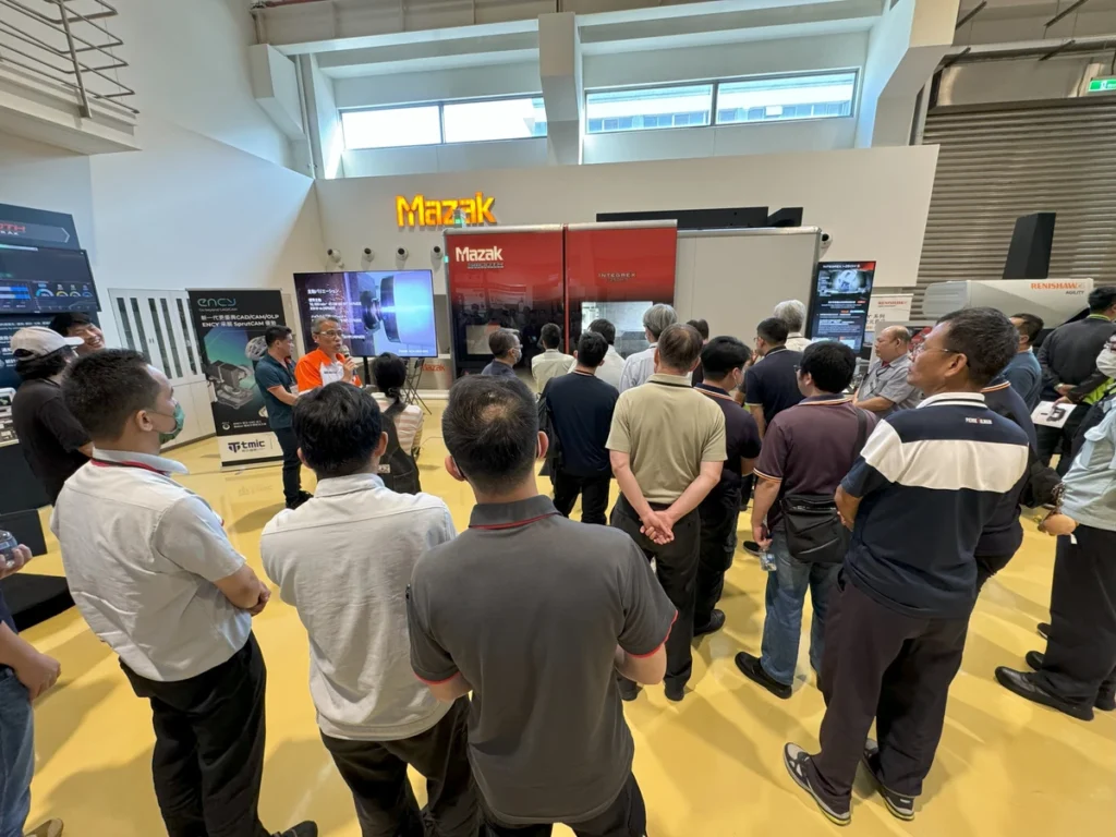 A group of people attentively watches a presentation at an event.