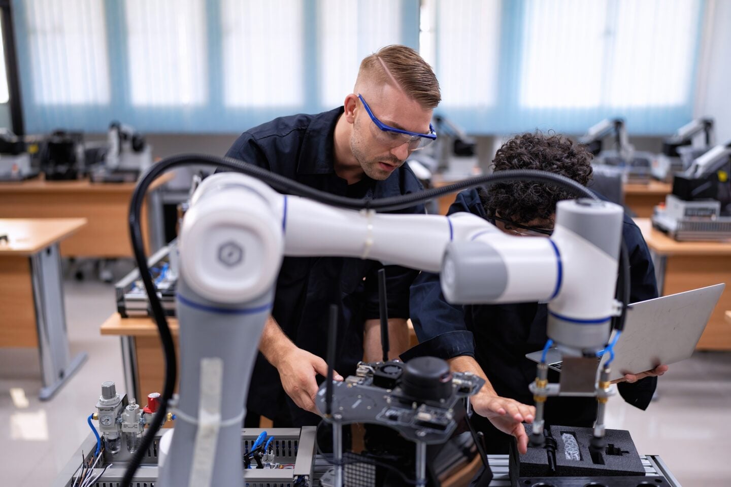 An engineer supervises robotic arms in a fabrication room.