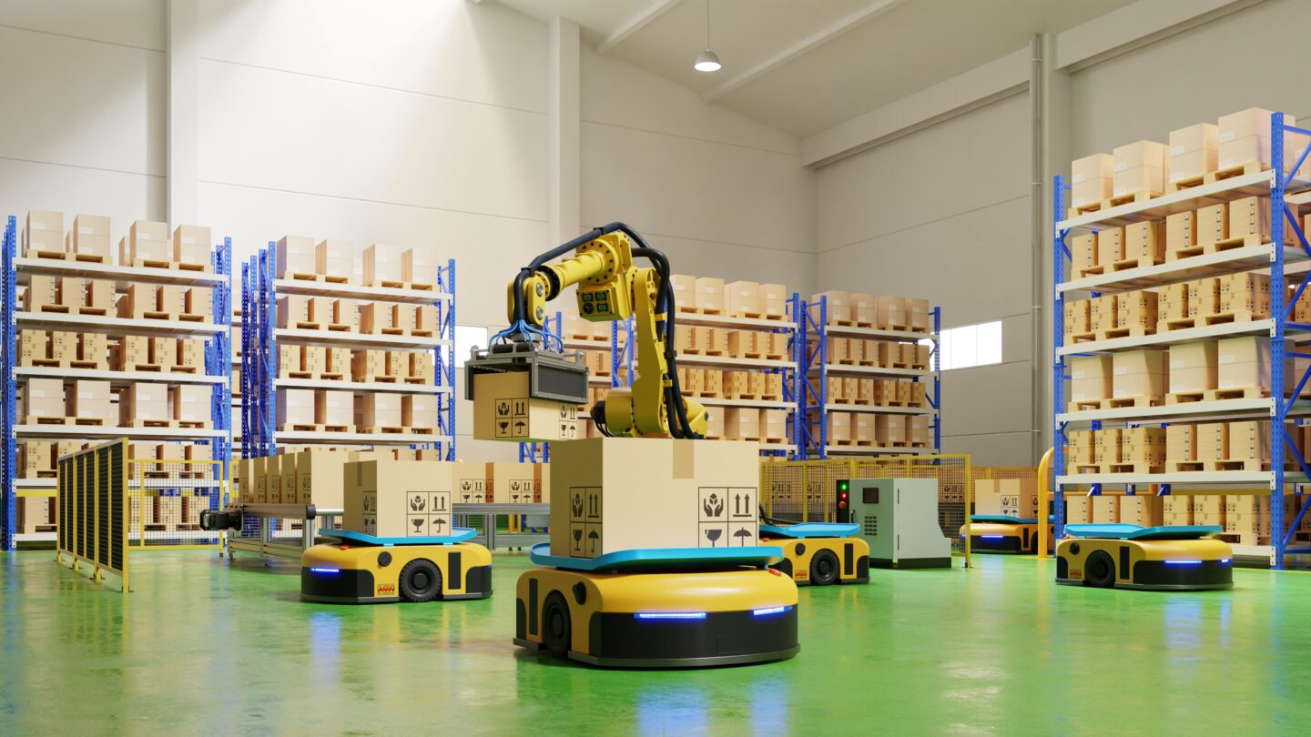 A robotic arm lifts a box while automated guided vehicles move around a warehouse.
