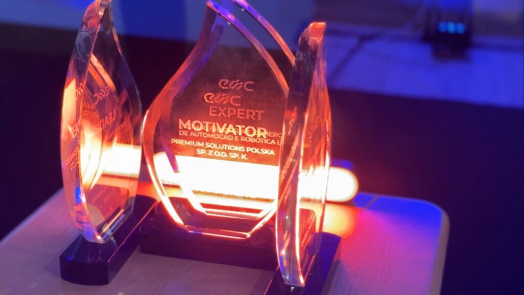 A crystal trophy with engraved text reflects colorful lighting.
