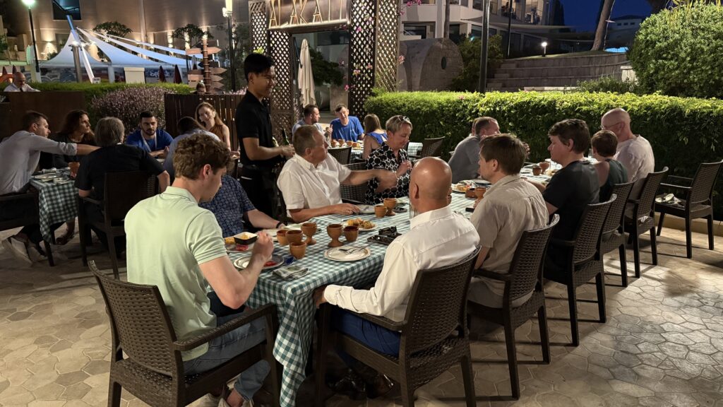 A group of people enjoys dinner together at an outdoor restaurant.
