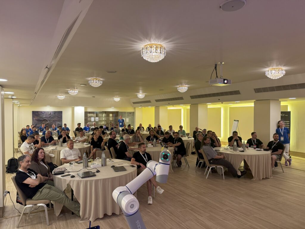 A conference room filled with attendees and a robot assisting.