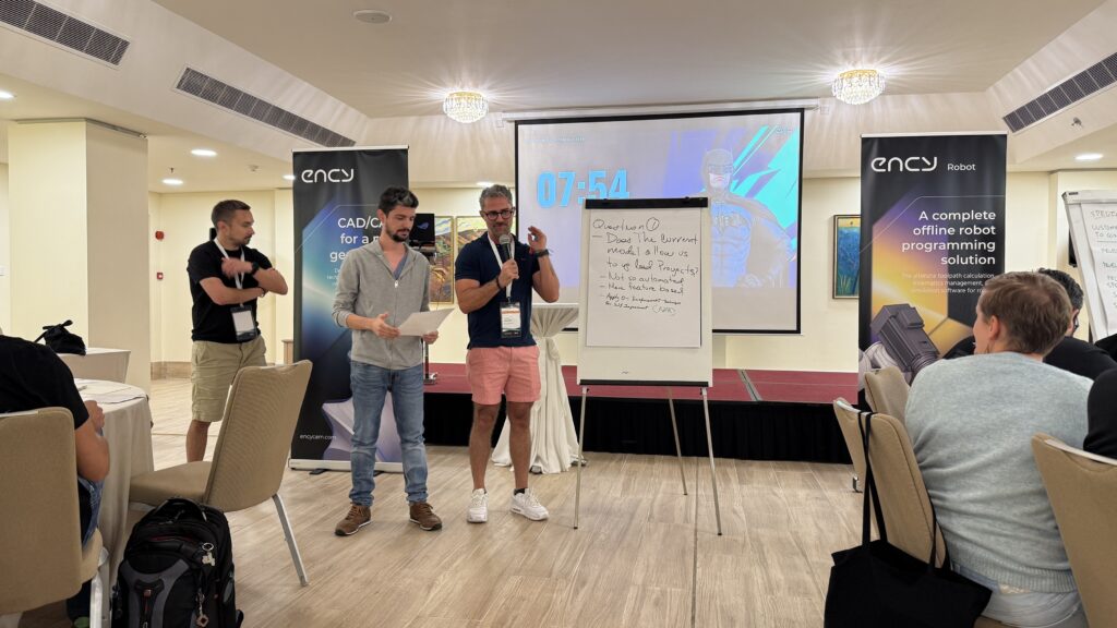 Two men stand in front of a flip chart, engaging an audience.