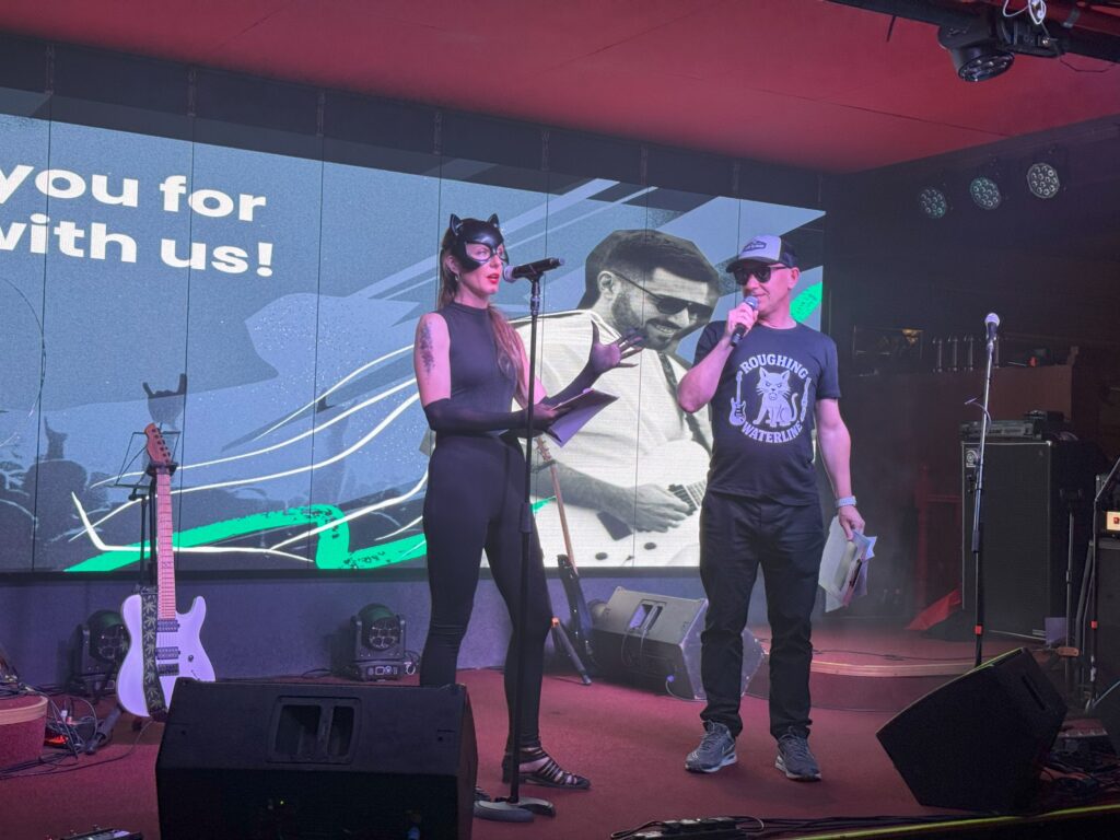 A woman in cat ears and a man sing duet on stage.