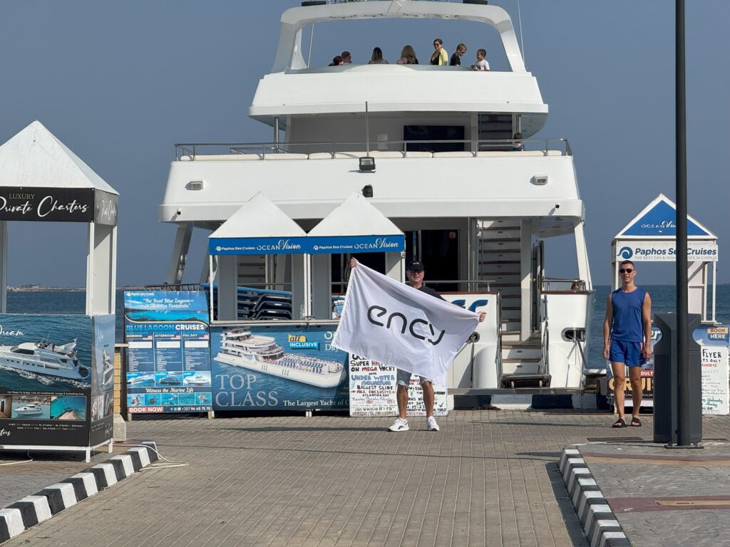 A person holds a flag while approaching a yacht at the dock.