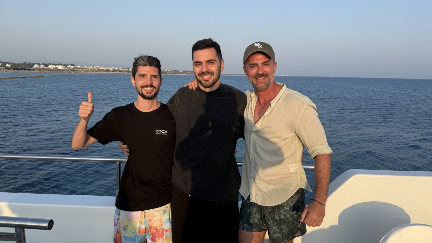 Three friends pose together on a boat against a serene ocean backdrop.