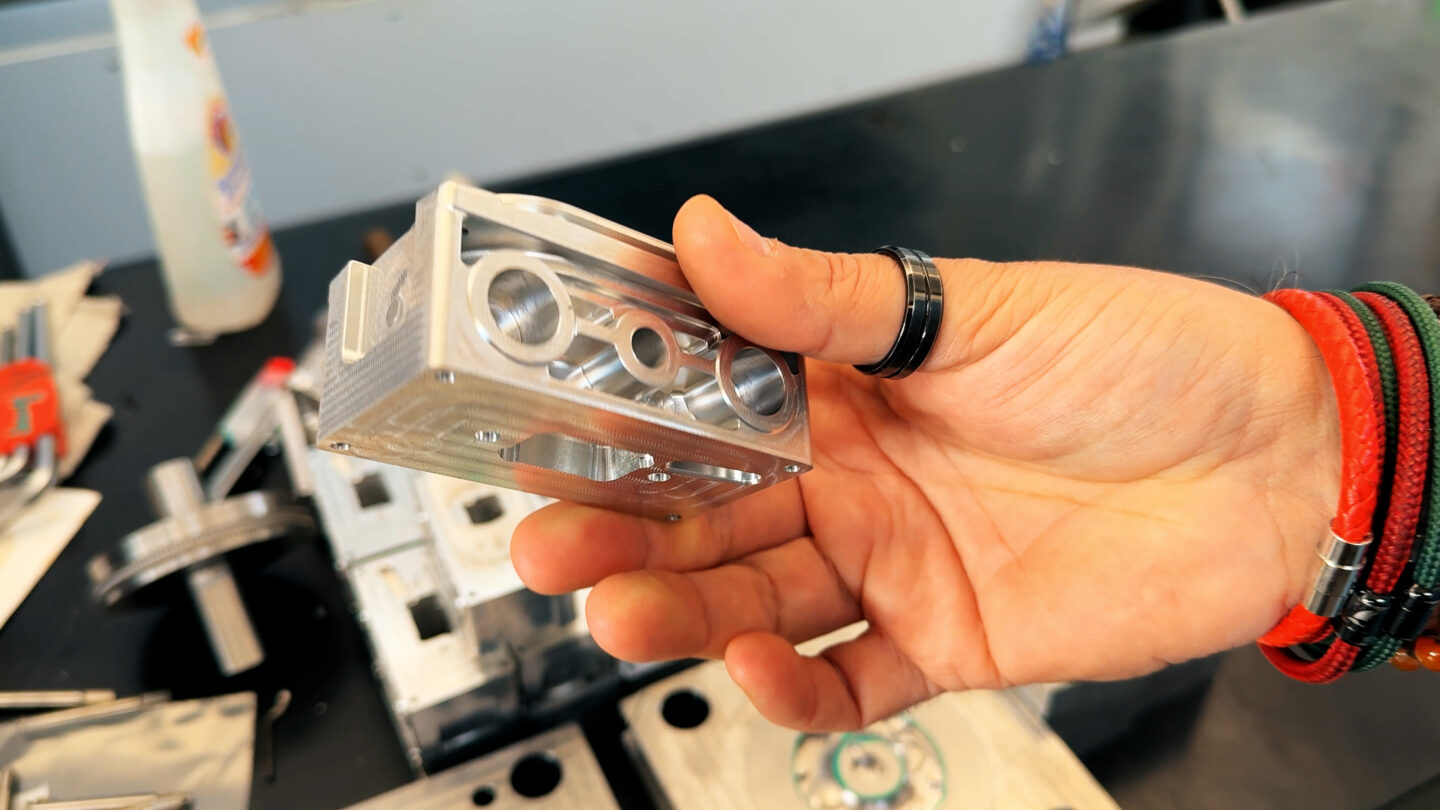 A hand holds a metallic cassette tape amidst other cassettes on a table.