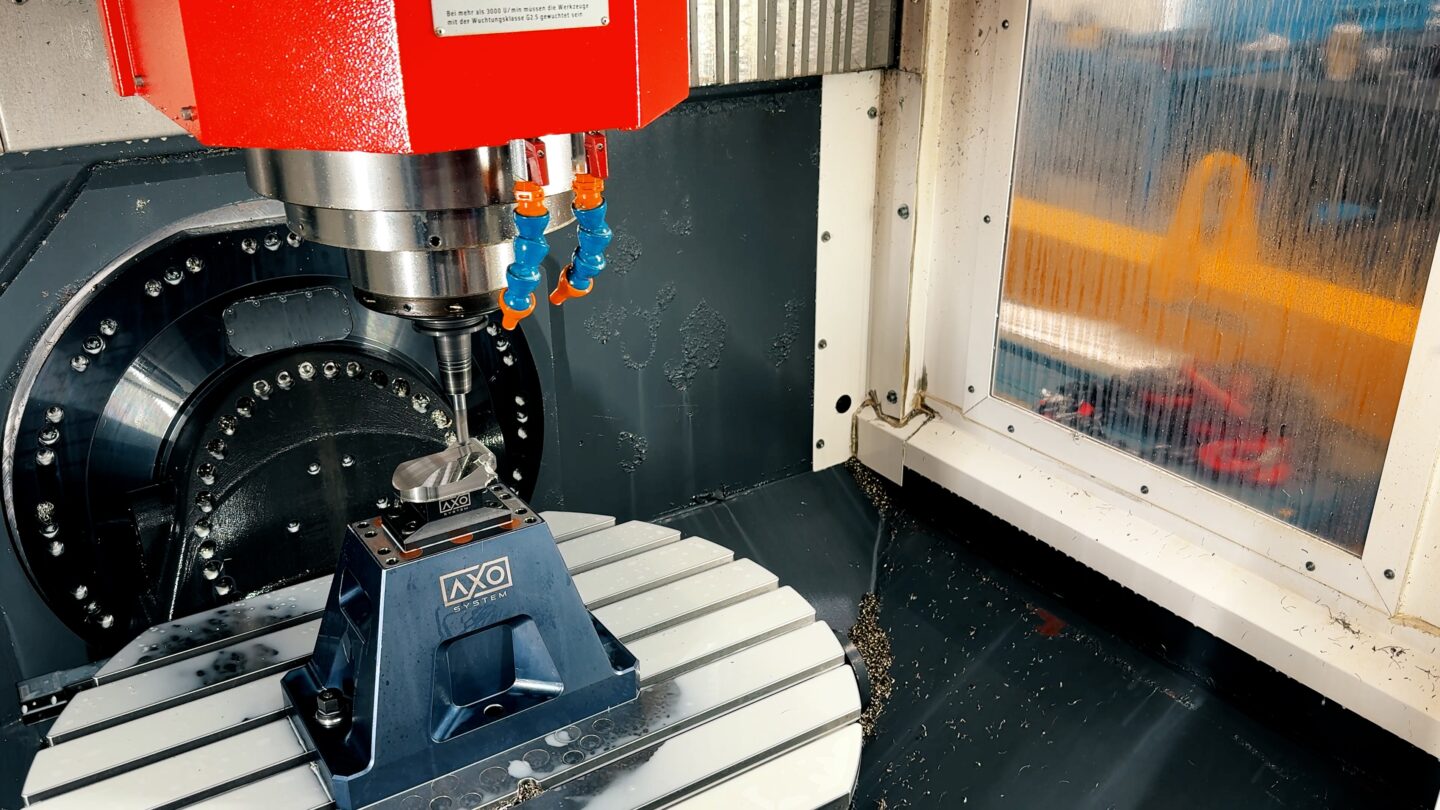 A CNC machine tool is actively drilling a metal workpiece.
