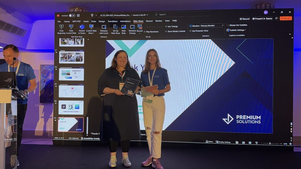 Two women stand together on stage, holding an award during an event.
