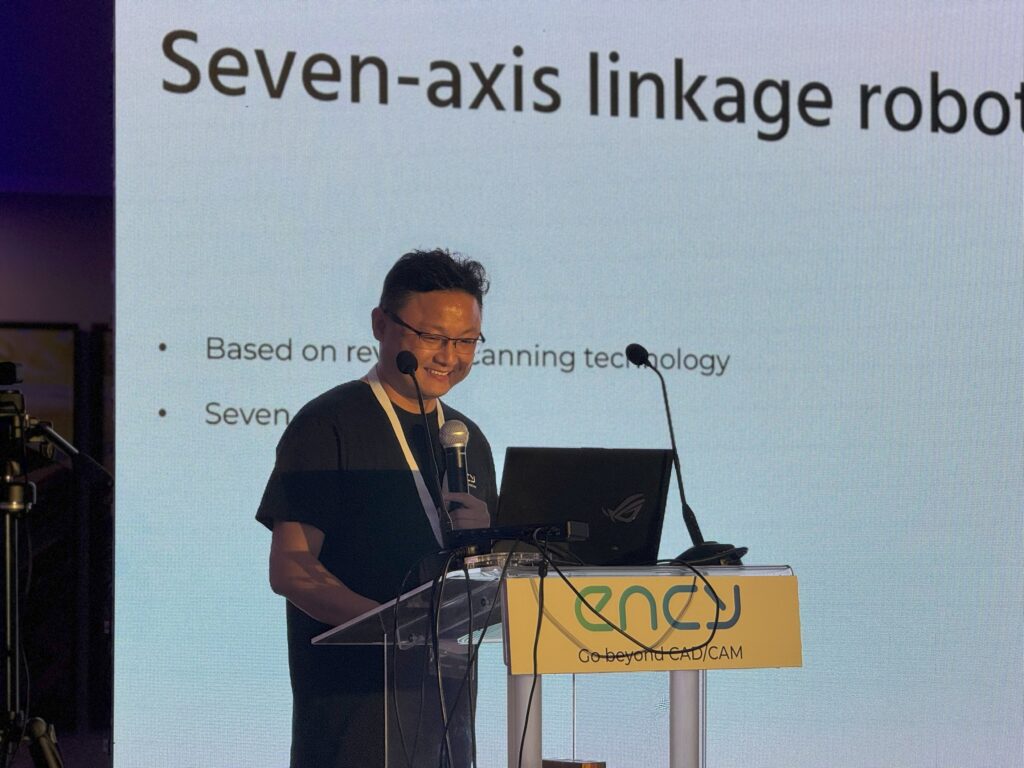 A presenter discusses seven-axis linkage robotics at a conference.