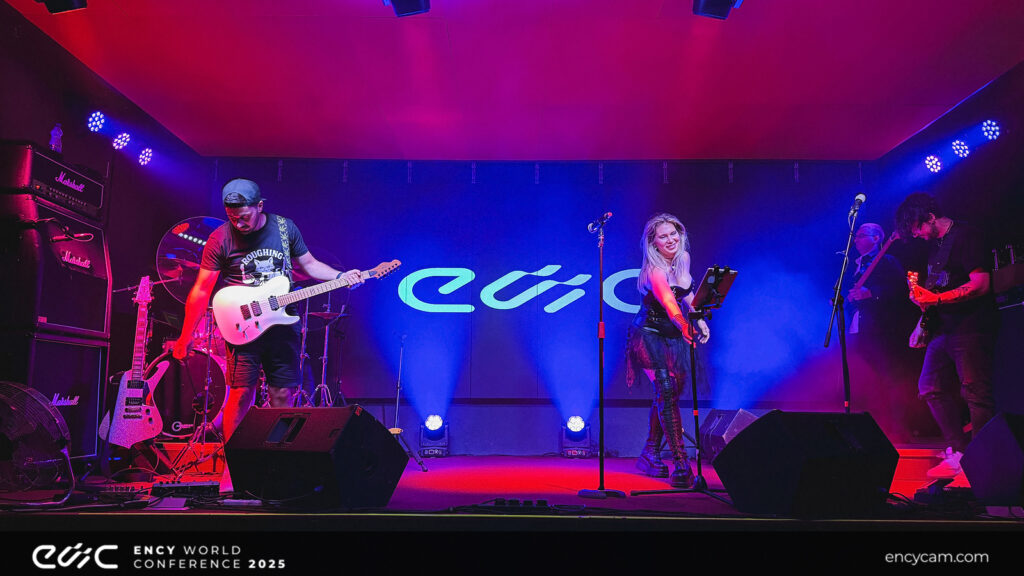 A musician performs on stage with a guitarist beside her.