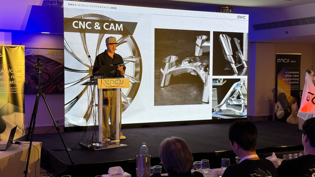 A speaker presents on CNC and CAM technology at a conference.