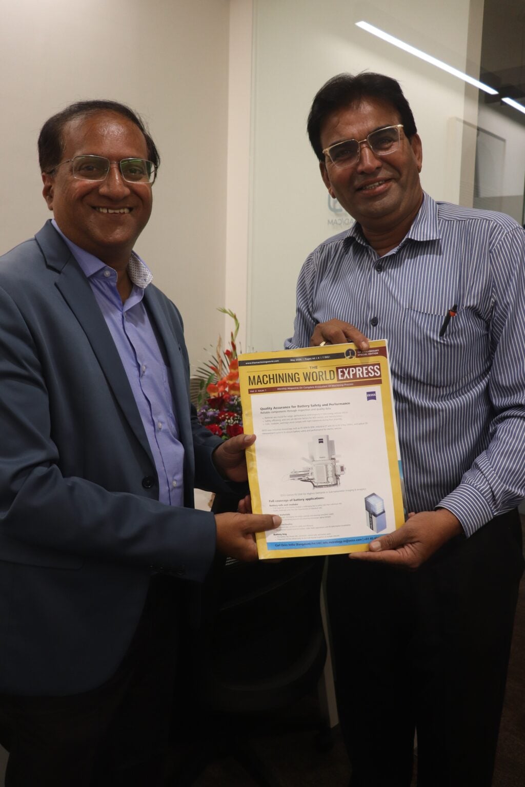 Two men are smiling while holding a certificate in an office setting.