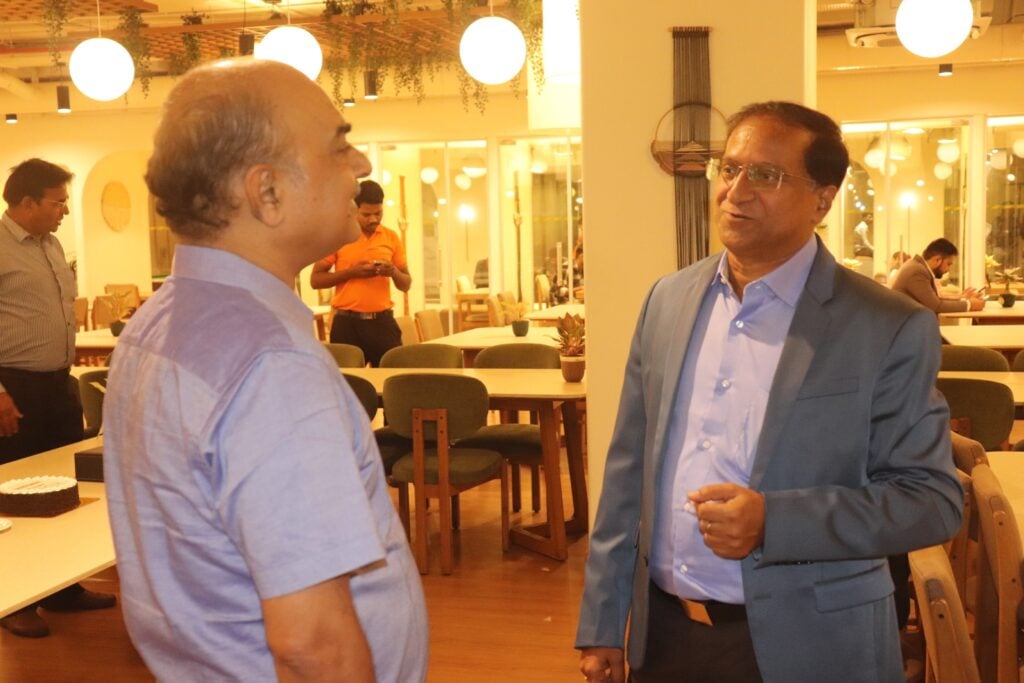 Two men engaged in a conversation in a well-lit indoor setting.