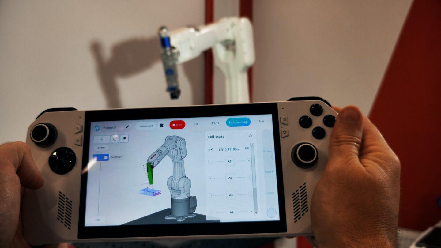 A person operates a robotic arm using a touchscreen interface.
