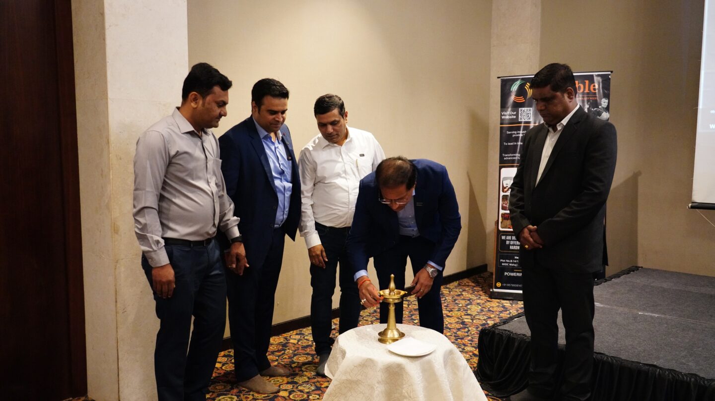A group of men observe as one lights a ceremonial lamp.