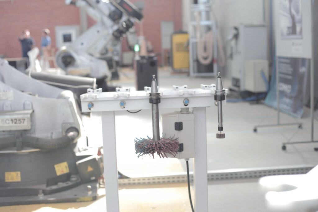 A machinery setup features a rotating brush mounted on a stand.