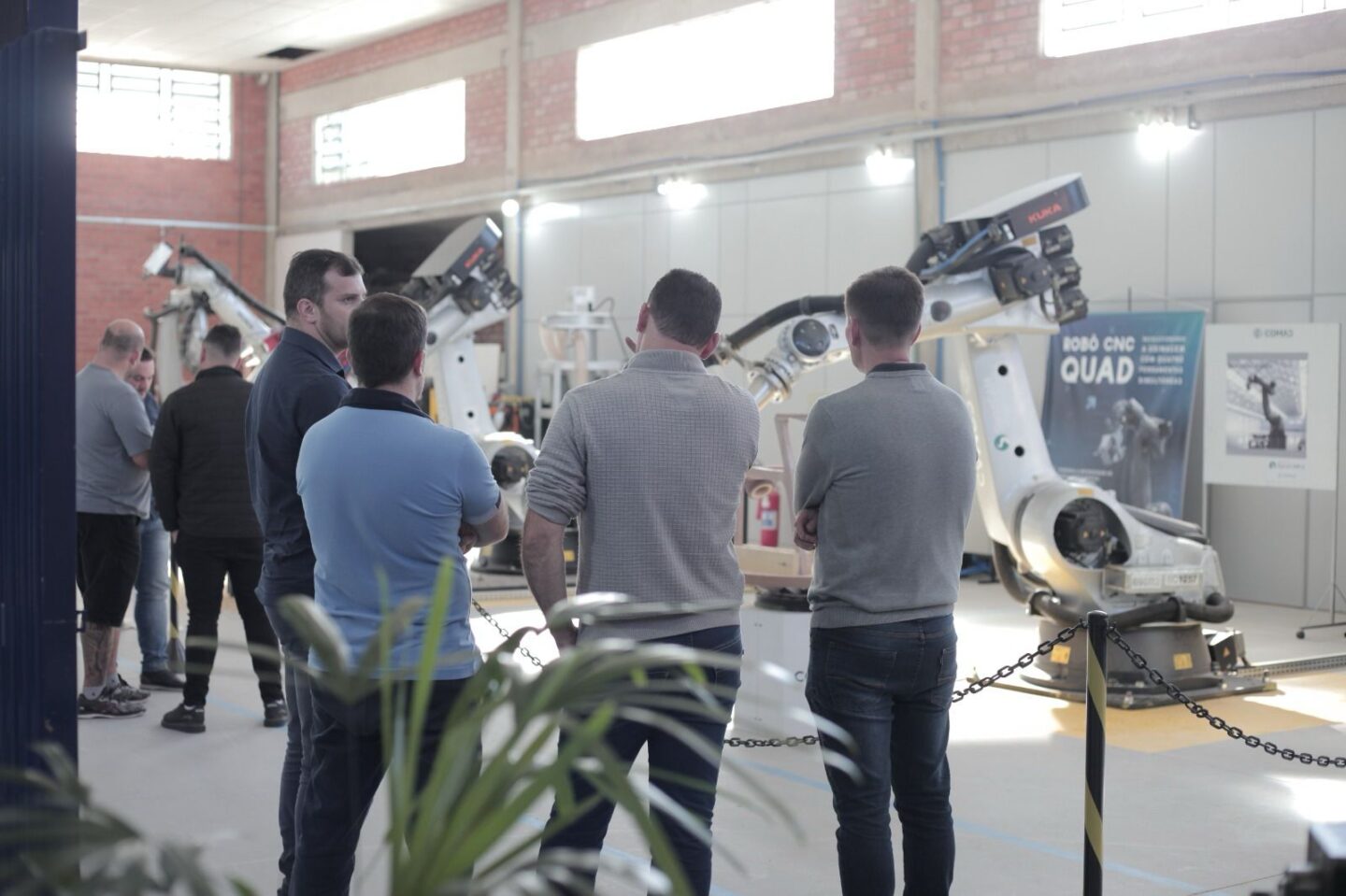 A group of people observes robotic technology in an industrial setting.