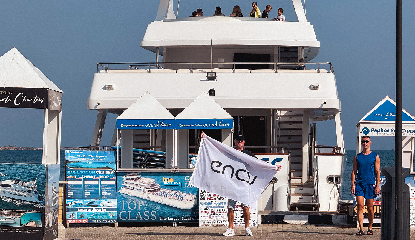 A person waves a flag in front of a yacht and dock area.