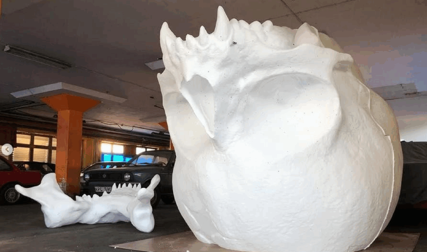 A large white sculpture resembling an animal's head is displayed indoors.