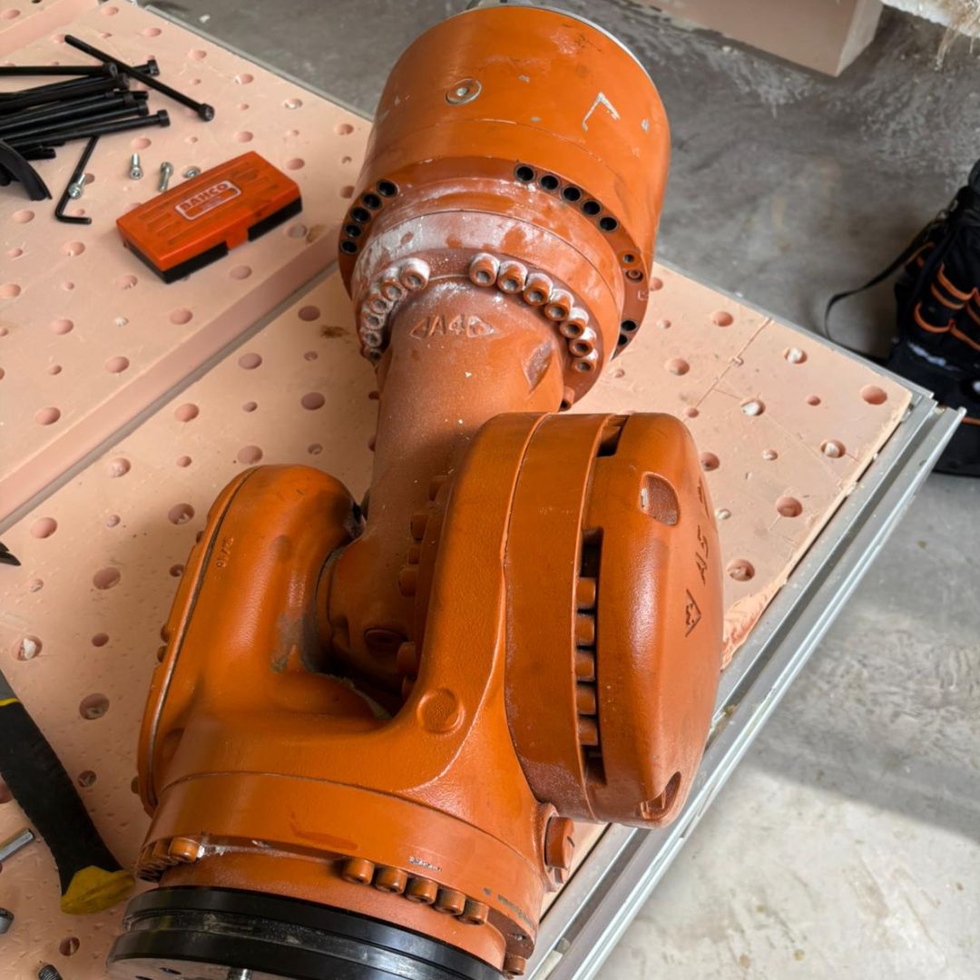 Bright orange industrial robot arm enclosed behind clear panels in a workstation labeled 'TRIM CELL'