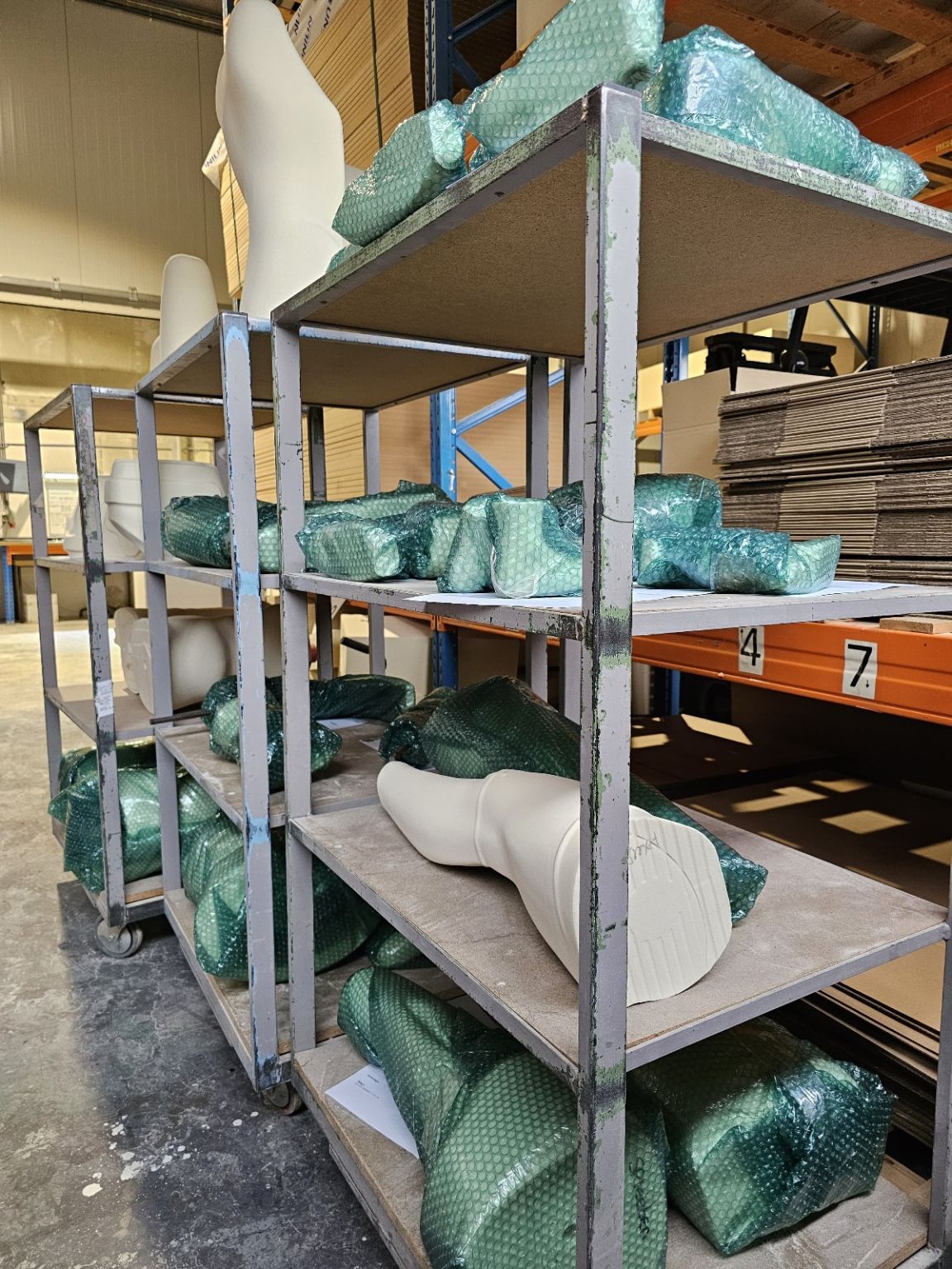 Six-axis industrial robot arm milling a light-colored foam or composite block into a contoured shape in an automated machining cell