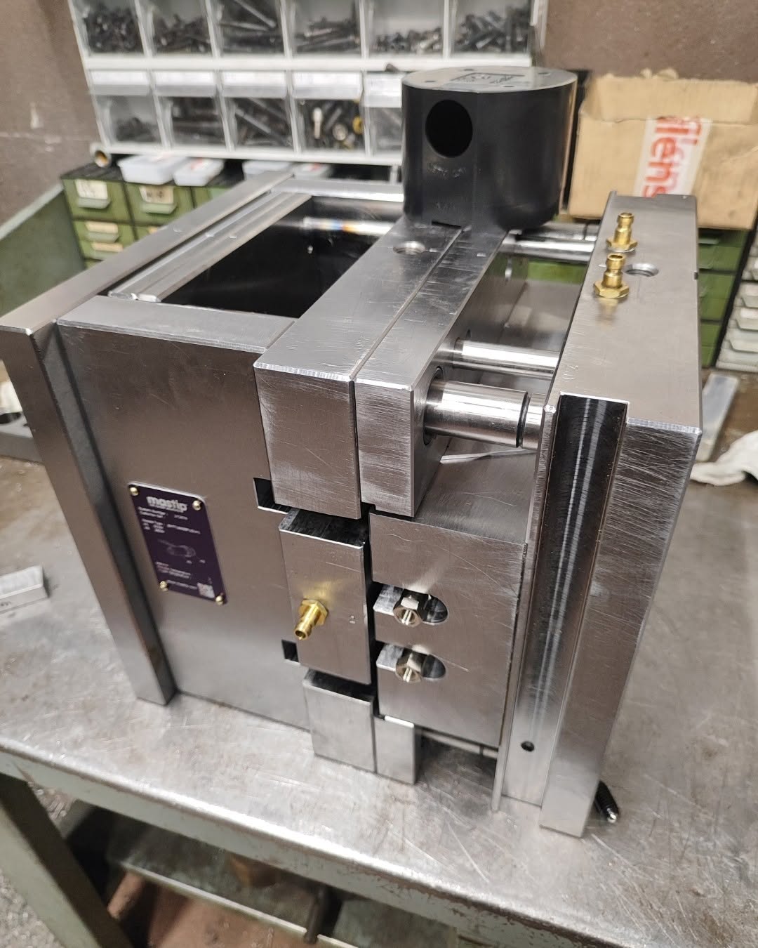 Polished two-part steel mold block for plastic injection molding on a workshop bench