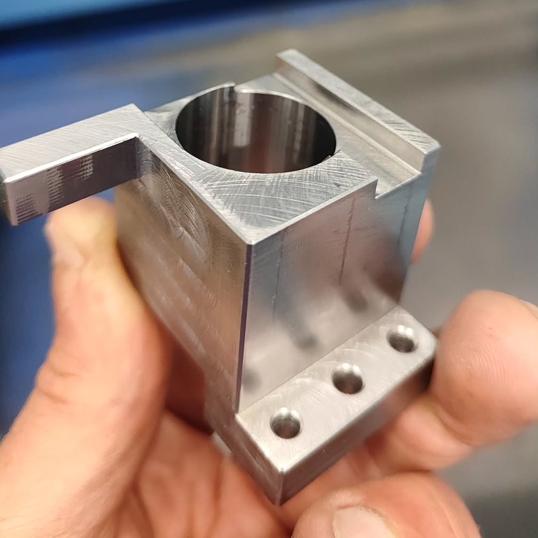 Close-up of a CNC-machined aluminum bracket with cylindrical bore and mounting holes