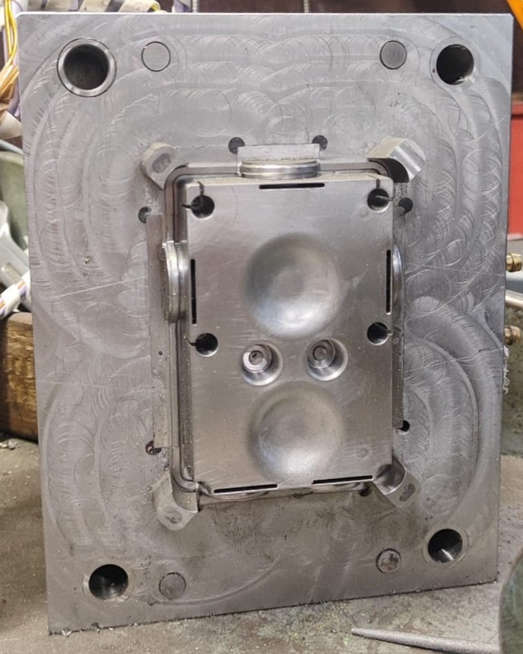 Close-up of a machined steel mold half with cavity depressions and concentric milling marks