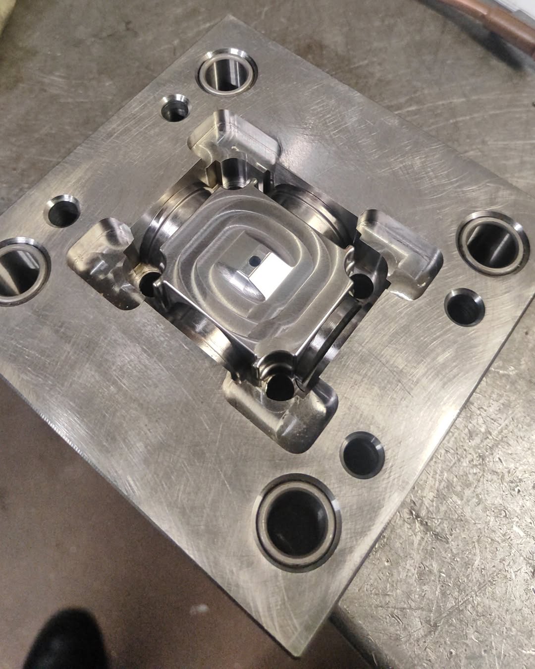 Close-up of a hardened steel mold insert with a machined cavity and milling marks