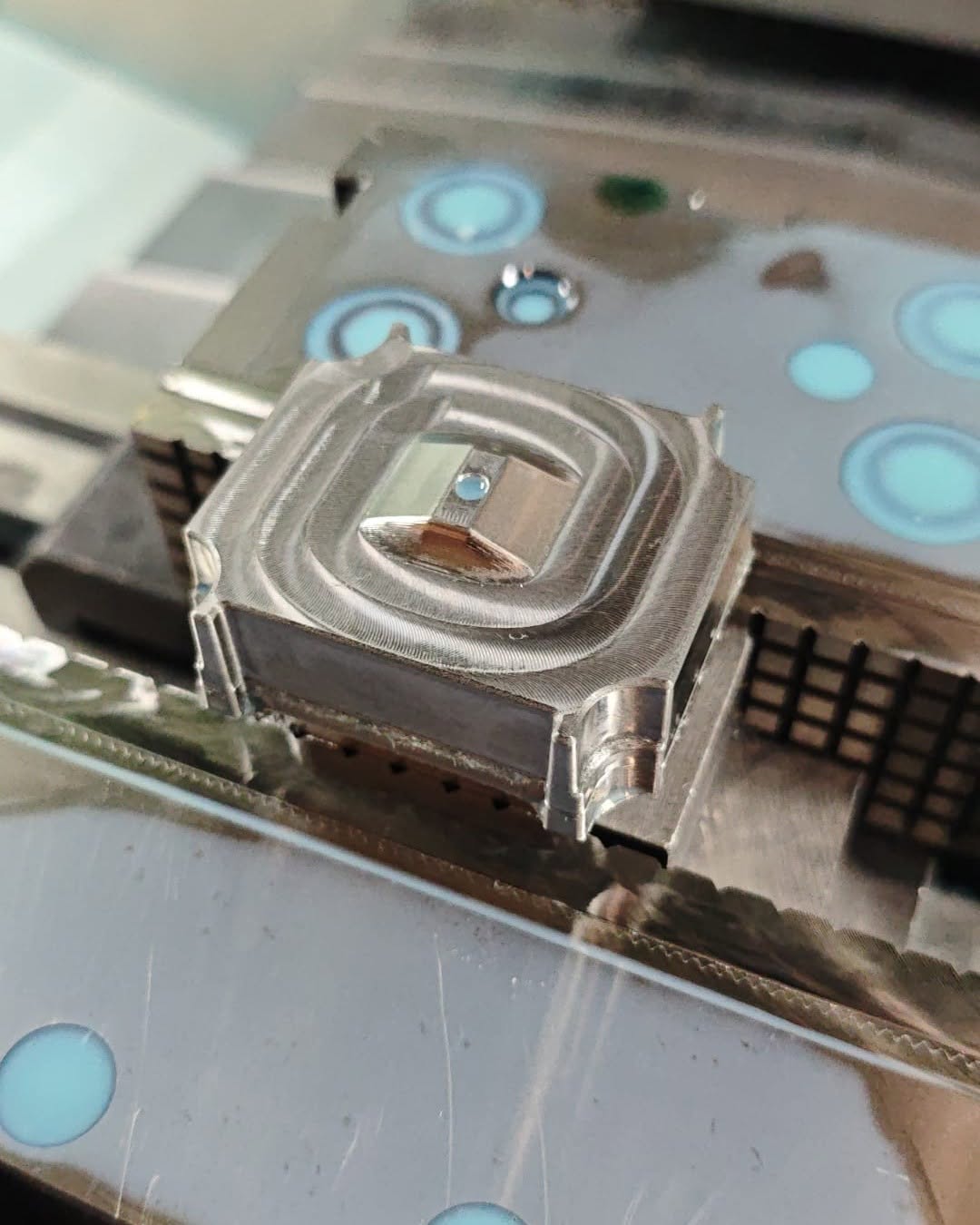 Machined aluminum insert with concentric tool marks on stepped surfaces inside a CNC milling machine