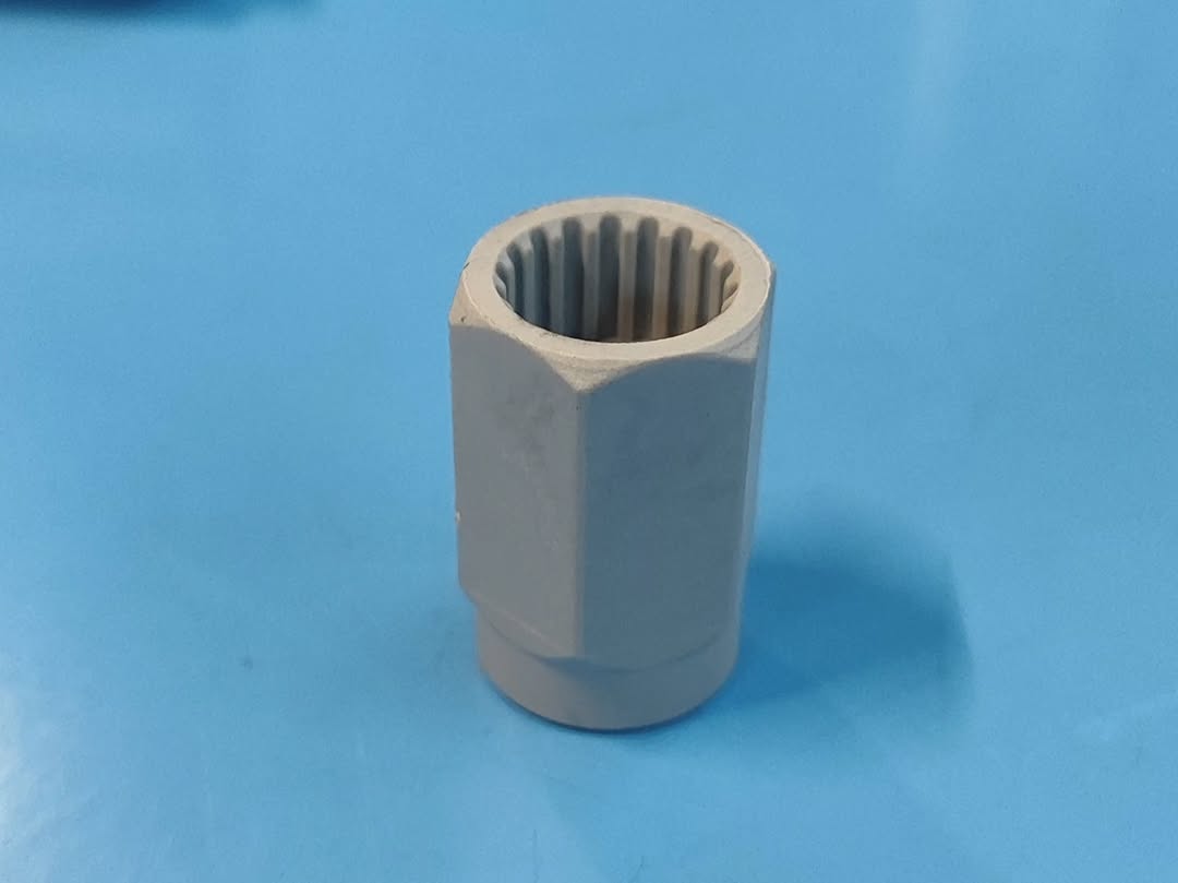 Close-up of a cylindrical spline coupling with internal gear teeth on a blue workbench mat