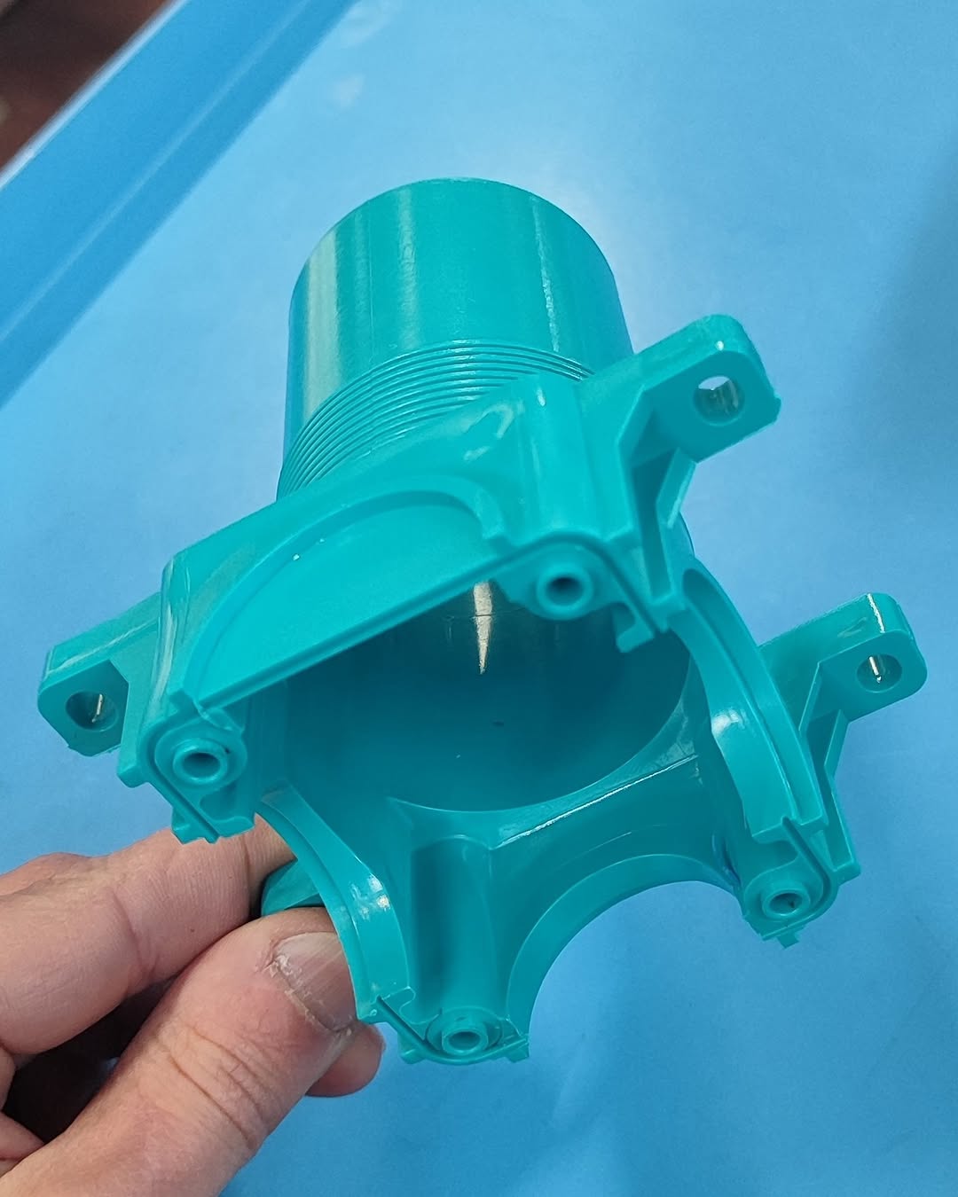 Teal-colored polymer housing with internal screw threads and external mounting lugs