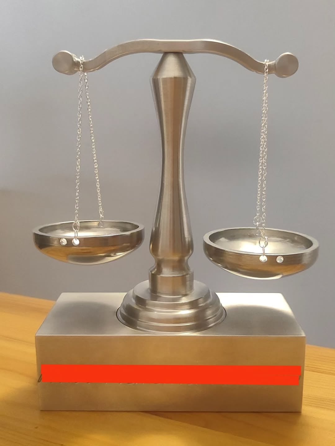 Polished metal model of a two-pan balance scale CNC-milled from a solid billet, showing smooth contours and tool paths