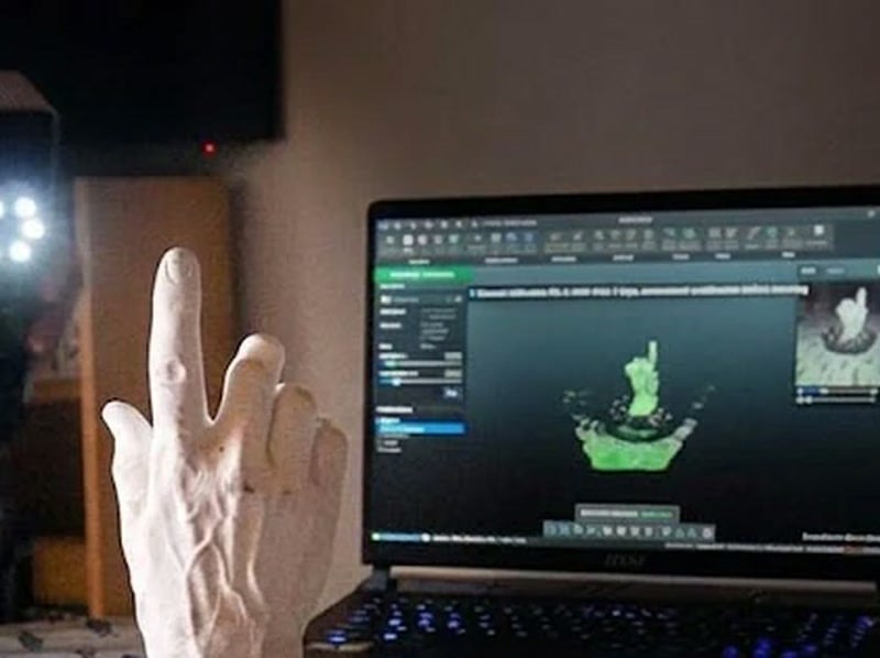 Original hand sculpture being digitised with a 3DeVOK 3D scanner, scan mesh shown on a laptop