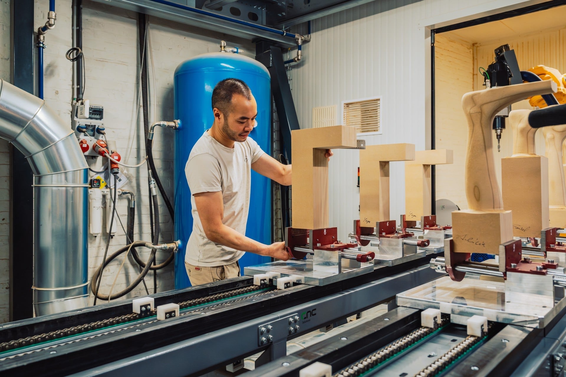 Operator securing workpieces onto pallets on the infeed conveyor