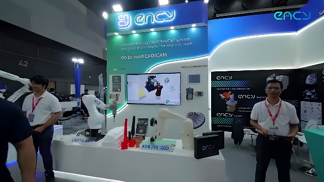 Two ABB IRB 1200 industrial robot arms on display at a trade show booth with a CAD/CAM system