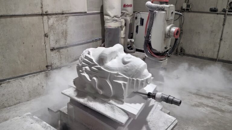 Foam block being CNC-milled into an organic relief form with a visible end mill and dust collector