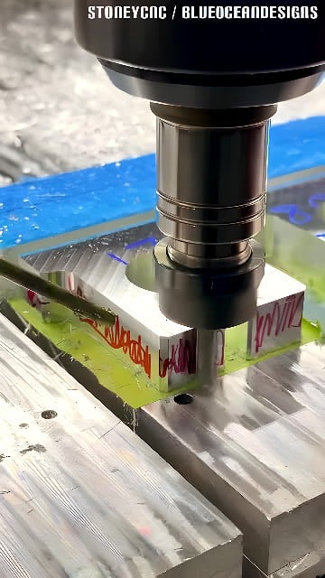 Vertical CNC milling machine cutting stepped pockets into a clamped aluminum billet with coolant