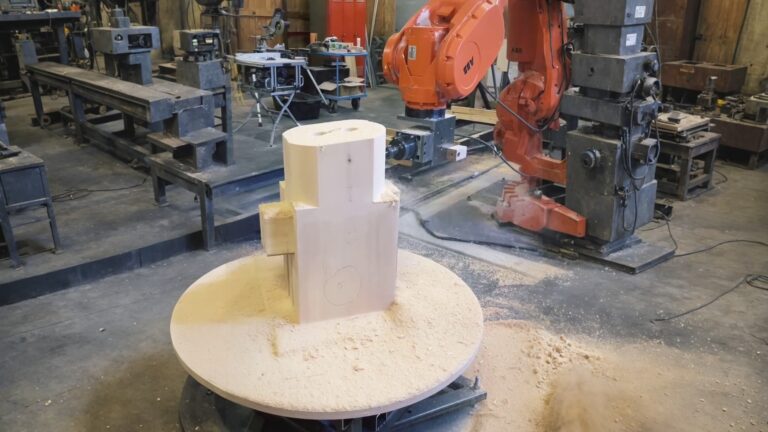 ABB six-axis industrial robot milling a large wooden block in a workshop