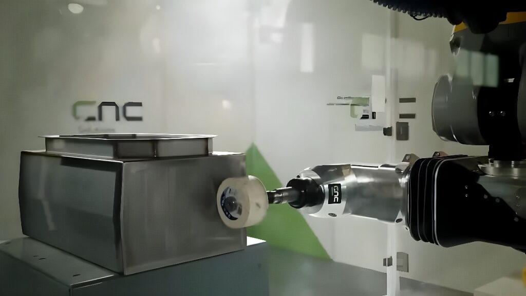 Six-axis industrial robot deburring and polishing a welded stainless-steel sheet-metal enclosure