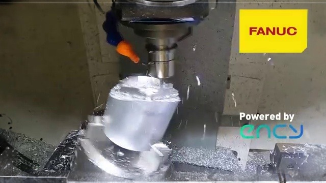 FANUC CNC vertical milling machine face-milling a rotating aluminum cylinder with coolant and metal chips