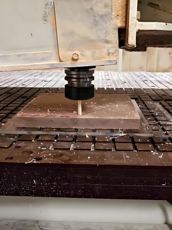 CNC milling machine using an end mill to machine a rectangular metal plate clamped to a T-slot table
