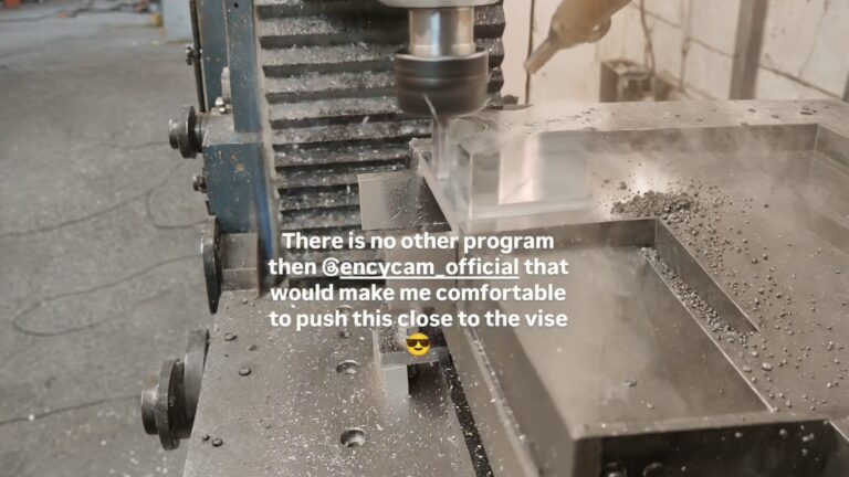 A benchtop CNC mill machining a clear acrylic rectangular block with a face-mill cutter and coolant nozzle