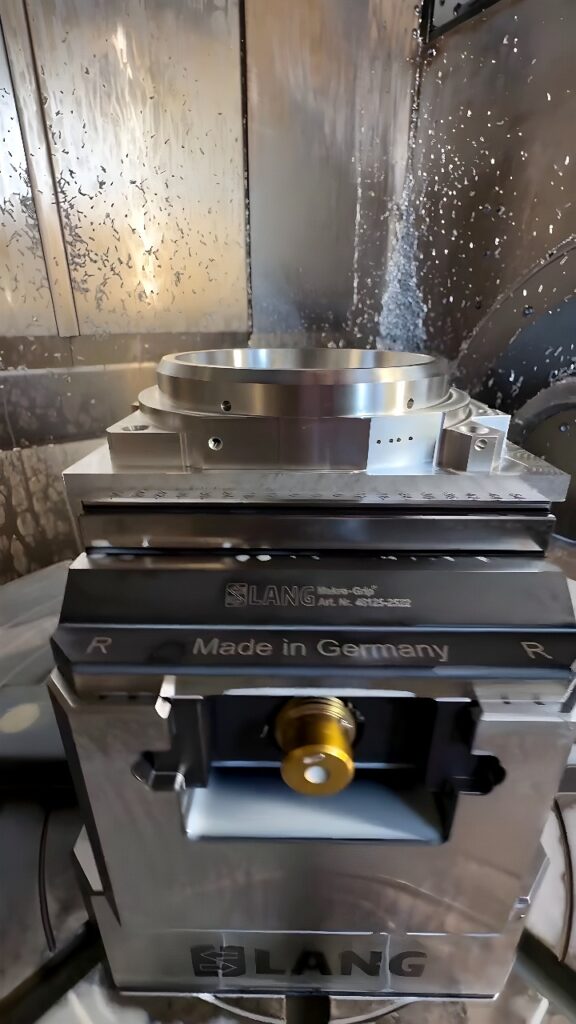 LANG precision vise holding a circular metal workpiece inside a CNC milling machine during active machining