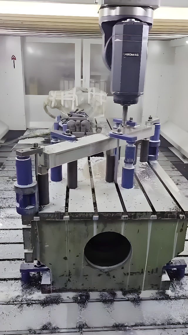 Vertical CNC milling center end-milling a metal housing blank with rotating cutter and custom fixture
